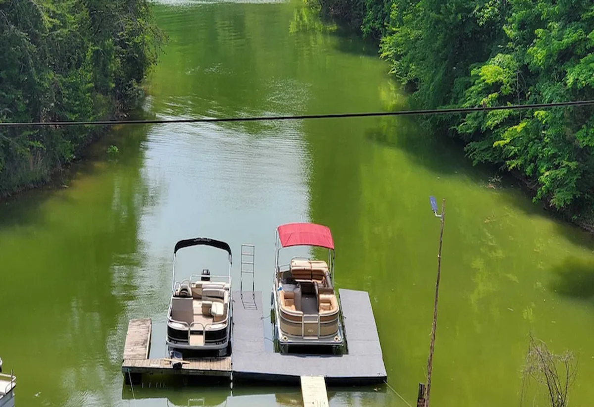 Two boats rest on a dock with calm water and lush greenery in the background, setting a serene lakeside scene ideal for swimming, boating, fishing, or just enjoying the tranquil view.