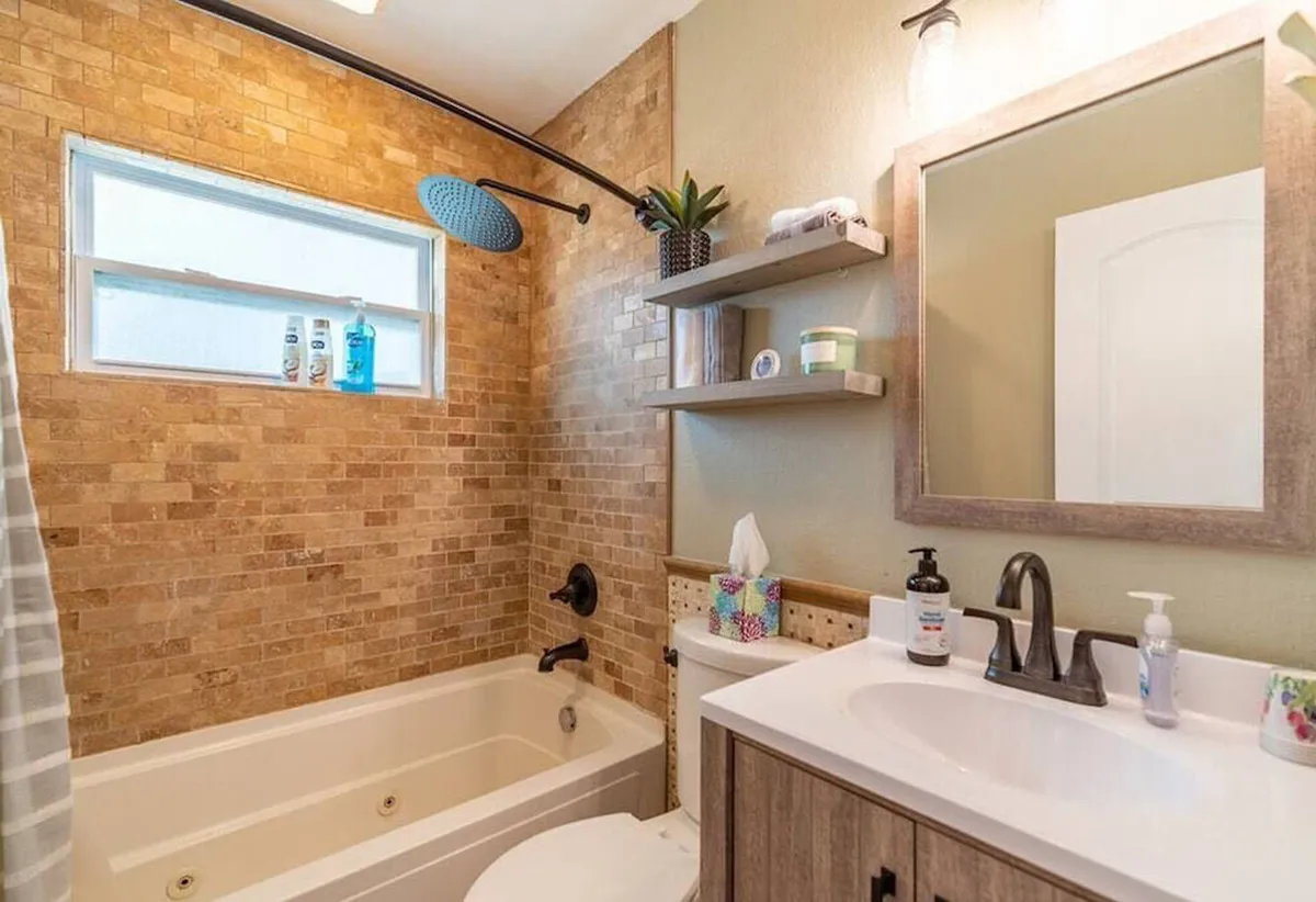 A bright and refreshing bathroom featuring a bathtub, showerhead, shelves, and a mirror. The space feels serene, organized, and spa-like, with amenities that invite relaxation and self-care.
